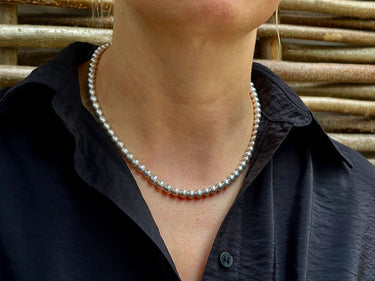 Perlenkette Monja am Hals getragen, silbergraue Perlen zu dunkelblauer Bluse mit Kragen
